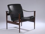 une image représentant un fauteuil en cuir noir posé sur un sol blanc