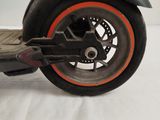 a black scooter with orange rims on a white surface
