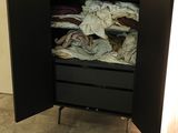 a black cabinet with clothes in it in a room