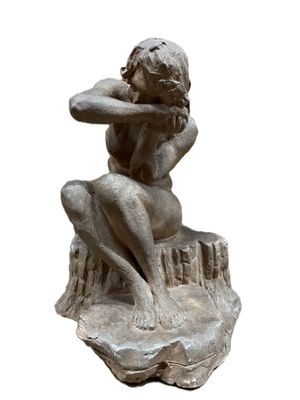 statue d'une femme assise sur un rocher, les mains sur la tête