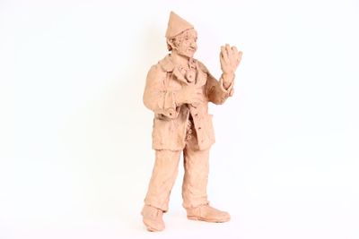 une statue en argile représentant un homme portant un chapeau et une veste