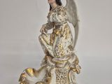 figurine of an angel sitting on a pedestal with a white background