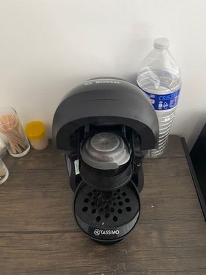 a black coffee maker on a wooden table next to a bottle of water