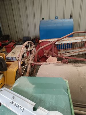 a pile of junk in a garage with a tractor in the background