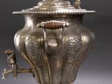 an antique silver plate with a silver teapot and a silver cup on it