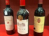 trois bouteilles de vin sont alignées sur une table rouge