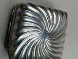 a silver object on the wall with a white background