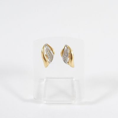 a pair of gold and diamond earrings on a clear stand