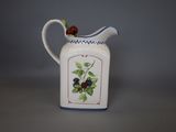 a small white pitcher with berries on it on a table