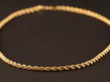 un collier en or avec un motif tressé sur fond noir