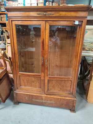 a wooden cabinet with a glass door and a chair