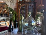 bottles and vases on a table in a room with a mirror in the background