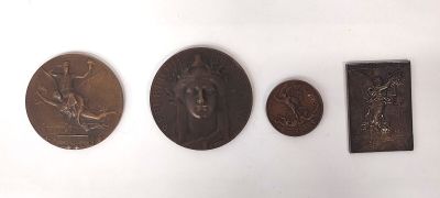 Plusieurs médailles de bronze sont exposées sur un mur blanc dans une pièce