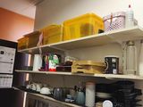 a kitchen with a refrigerator, sink, and shelves with dishes on it