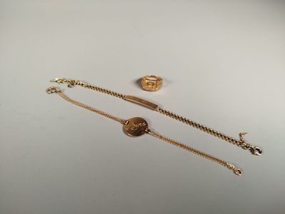 a close up of a gold bracelet and a gold ring on a white surface