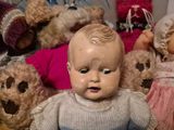 a lot of stuffed teddy bears and a baby doll in a pile