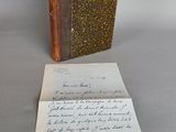 un vieux livre posé sur une table à côté d'une feuille de papier
