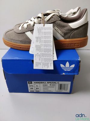 une paire de baskets adidas posée sur une boîte bleue