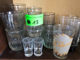 plusieurs verres et une bouteille d'alcool sur une étagère