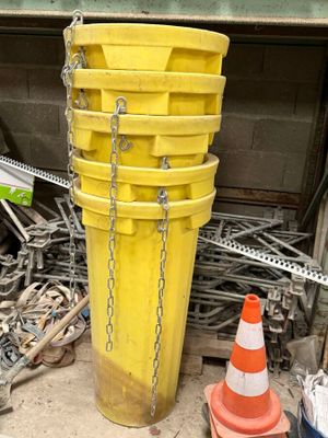 un seau jaune auquel sont suspendues des chaînes, à côté d'un tas de matériel de chantier
