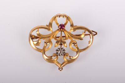 a close up of a gold brooch with a red stone in the center