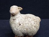 une petite statue représentant un mouton posée sur une surface noire