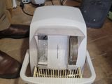 un micro-ondes blanc posé sur le sol à côté d'une paire de chaussures marron