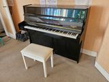 a piano and a stool in the corner of a room