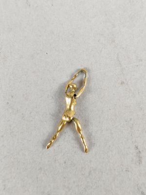 a gold ballerina charm on a white surface