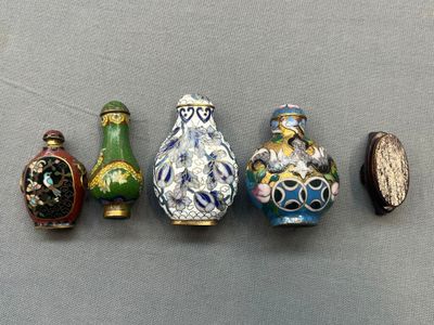 quatre vases de couleurs différentes sont alignés sur une surface grise
