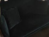 black velvet sofa in a corner of a room next to a wall
