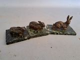 three statues of rabbits sitting on top of a marble block