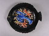 une assiette noire ornée de fleurs bleues et orange