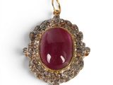 a close up of a red stone and diamond pendant