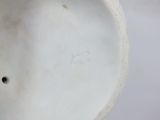 a close up of a white vase with a hole in it