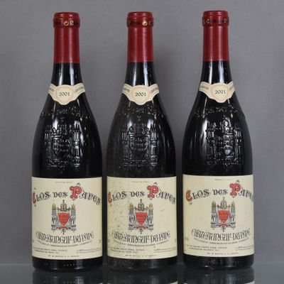 three bottles of red wine sit on a glass table