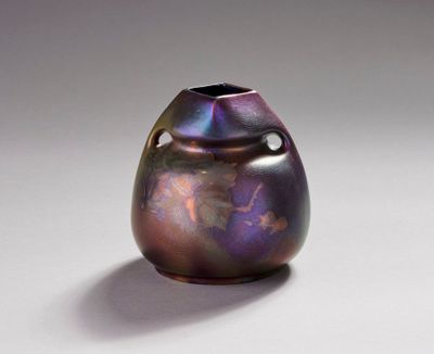 un vase violet posé sur une surface blanche