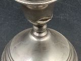 a silver candle holder on a table with a black background