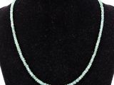 Le collier est composé de perles de verre et comporte une perle verte.