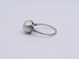 a white pearl and diamond ring on a white surface