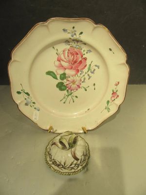 a white plate with a pink rose on it next to a gold ring
