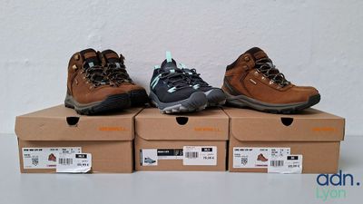 three pairs of hiking shoes sitting on top of boxes on a table