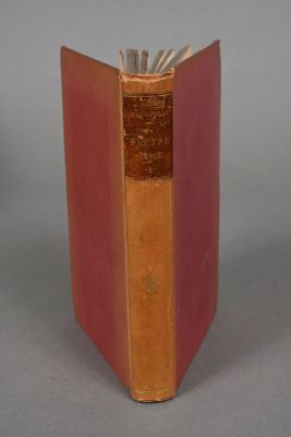 an old book sitting on top of a table on a gray surface