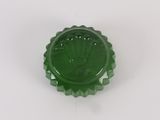 green glass bottle cap with a crown on it on a white surface