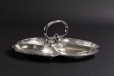 une assiette en argent plaqué, surmontée d'un anneau, posée sur une surface noire