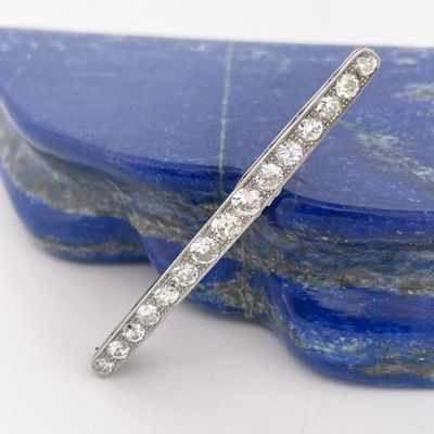 a close up of a diamond bar broochle on a blue stone