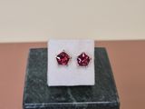 a pair of pink earrings sitting on top of a marble block