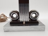 a silver and black clock on a stand with a cord