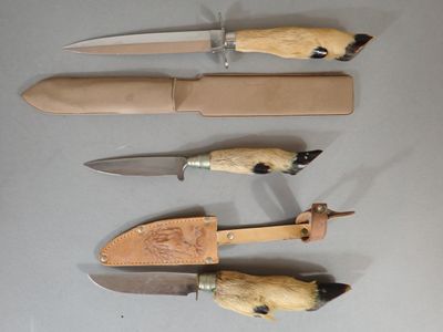 several knives are lined up on a table with a leather case