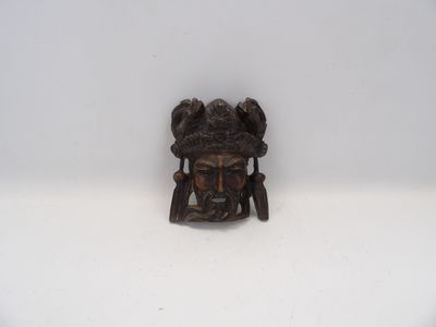 l'image d'un petit masque en bronze sur un fond blanc